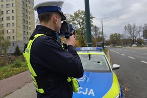 Zdjęcie przedstawia umundurowanego policjanta Wydziału Ruchu Drogowego podczas czynności służbowych.