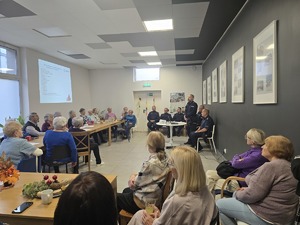 Zdjęcie przedstawia umundurowanych policjantów oraz uczestników debaty w sali.