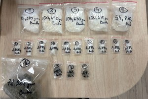 Zdjęcie przedstawia woreczki z zawartością białej substancji i suszu roślinnego leżące na stole.