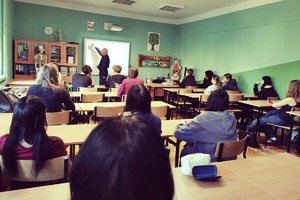 Zdjęcie przedstawia umundurowanego policjanta prowadzącego prelekcję w szkole.