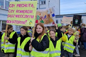 Zdjęcie przedstawia dzieci ubrane w kamizelki odblaskowe podczas wydarzenia.