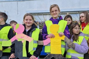 Zdjęcie przedstawia dzieci ubrane w kamizelki odblaskowe podczas wydarzenia.