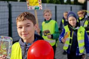 Zdjęcie przedstawia dzieci ubrane w kamizelki odblaskowe podczas wydarzenia.