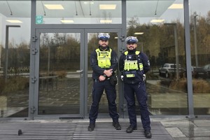 Zdjęcie przedstawia dwóch, umundurowanych policjantów z Wydziału Ruchu Drogowego na tle budynku komendy.