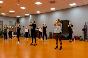 Zdjęcie przedstawia instruktora policyjnego prowadzącego zajęcia dla uczestniczek kursu w sali.