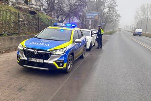 Zdjęcie przedstawia funkcjonariusza Wydziału Ruchu Drogowego sprawdzającego trzeźwość kierującego.