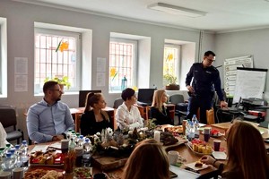 Zdjęcie przedstawia umundurowanego policjanta oraz prezentację multimedialną.