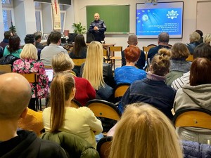 Zdjęcie przedstawia umundurowanego policjanta przemawiającego do uczestników spotkania.