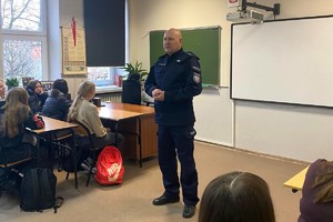 Zdjęcie przedstawia umundurowanego policjanta w sali podczas prelekcji z uczniami.