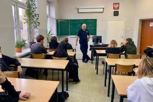 Zdjęcie przedstawia umundurowanego policjanta podczas prelekcji w sali.