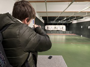 Zdjęcie przedstawia mężczyznę z bronią na terenie strzelnicy.