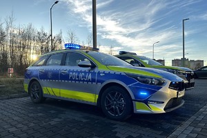 Zdjęcie przedstawia dwa oznakowane policyjne radiowozy na parkingu.