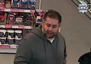 Zdjęcie przedstawia mężczyznę w szarej bluzie na terenie sklepu.