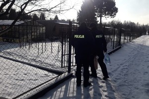 Zdjęcie przedstawia dwóch, umundurowanych policjantów na terenie ogródków działkowych.