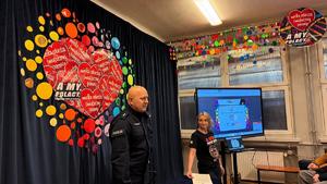 Zdjęcie przedstawia umundurowanego policjanta podczas spotkania z wolontariuszami.