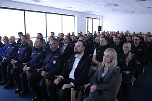 Zdjęcie przedstawia gości oraz policjantów podczas odprawy rocznej w sali.