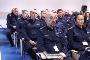 Zdjęcie przedstawia gości oraz policjantów podczas odprawy rocznej w sali.