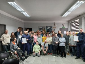 Zdjęcie przedstawia umundurowanych policjantów oraz uczestników spotkania w sali.