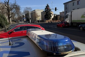 Zdjęcie przedstawia oznakowany radiowóz. W tle przejście dla pieszych.