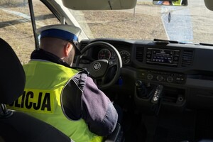 Zdjęcie przedstawia umundurowanego policjanta w samochodzie służbowym.