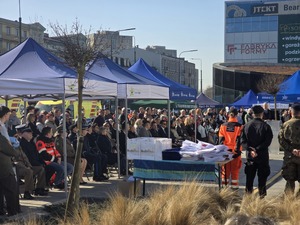 Zdjęcie przedstawia uczestników uroczystości na placu Dworca PKP.