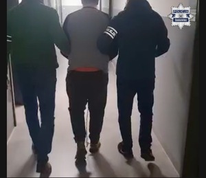 Zdjęcie przedstawia nieumundurowanych policjantów prowadzących zatrzymanego.