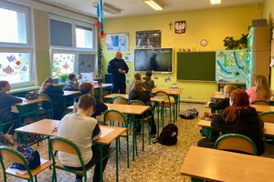 Umundurowany policjant w sali z uczniami.