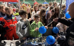 Umundurowany policjant z dziećmi przy stoisku.