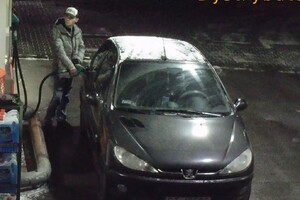 Mężczyzna w czapce tankujący paliwo na stacji benzynowej.