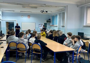 Policjant i kobieta podczas prelekcji w sali z uczniami.