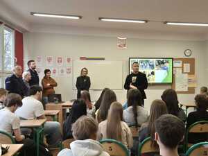 Zdjęcie przedstawia umundurowanych policjantów oraz pracowników MOPS Sosnowiec podczas spotkania profilaktycznego z uczniami.