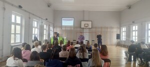 Zdjęcie przedstawia uczniów szkoły, pracowników MOPS oraz umundurowanego policjanta w szkole