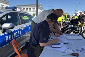 Zdjęcie przedstawia umundurowanego policjanta dokującego rejestracji roweru