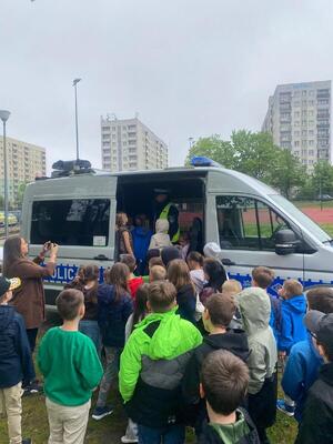 Zdjęcie przestawia radiowóz i uczniów szkoły.