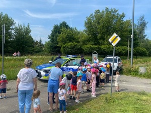 Zdjęcie przedstawia radiowóz, policjantów umundurowanych oraz grupę dzieci