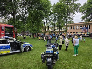 Zdjęcie przedstawia radiowóz, motocykl policyjny oraz grupę dzieci