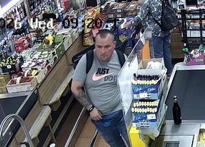 Mężczyzna w szarej bluzce z plecakiem na terenie sklepu.