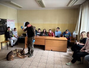 Przewodnik psa służbowego z wychowankami w komisariacie.