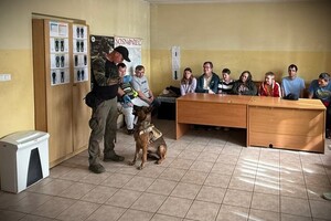 Przewodnik psa służbowego z wychowankami w komisariacie.
