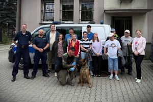 Wychowankowie oraz umundurowani policjanci pozujący do zdjęcia przed budynkiem.