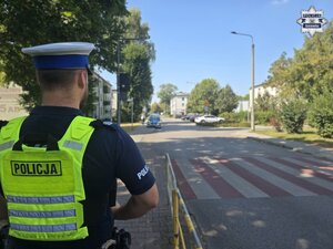 Umundurowany policjant przy przejściu dla pieszych w rejonie szkoły.