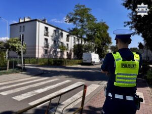 Umundurowany policjant przy przejściu dla pieszych w rejonie szkoły.