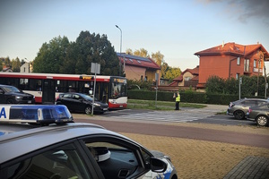 Umundurowany policjant z wydziału ruchu drogowego podczas pomiaru prędkości oraz oznakowany radiowóz.