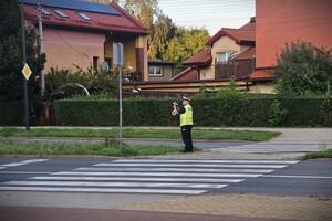 Umundurowany policjant z wydziału ruchu drogowego podczas pomiaru prędkości