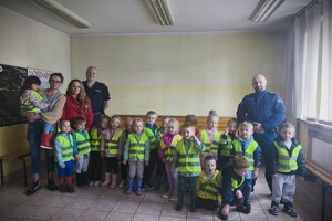 Dzieci oraz policjanci pozujący do zdjęcia w komisariacie.