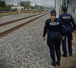 Umundurowani policjanci przy torach kolejowych.