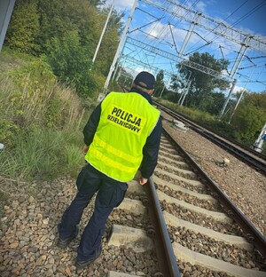 Umundurowany policjant przy torach kolejowych.